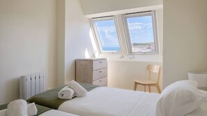 A bedroom with a bed, a chair, a nightstand, a dresser, and a window with a view. - Loft PENTHOUSE on the BEACH with 2 terraces (Zarautz)