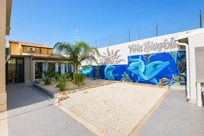 Ein Gebäude mit Wandgemälde von Delfinen und Sonne, einer Palme und blauem Himmel.