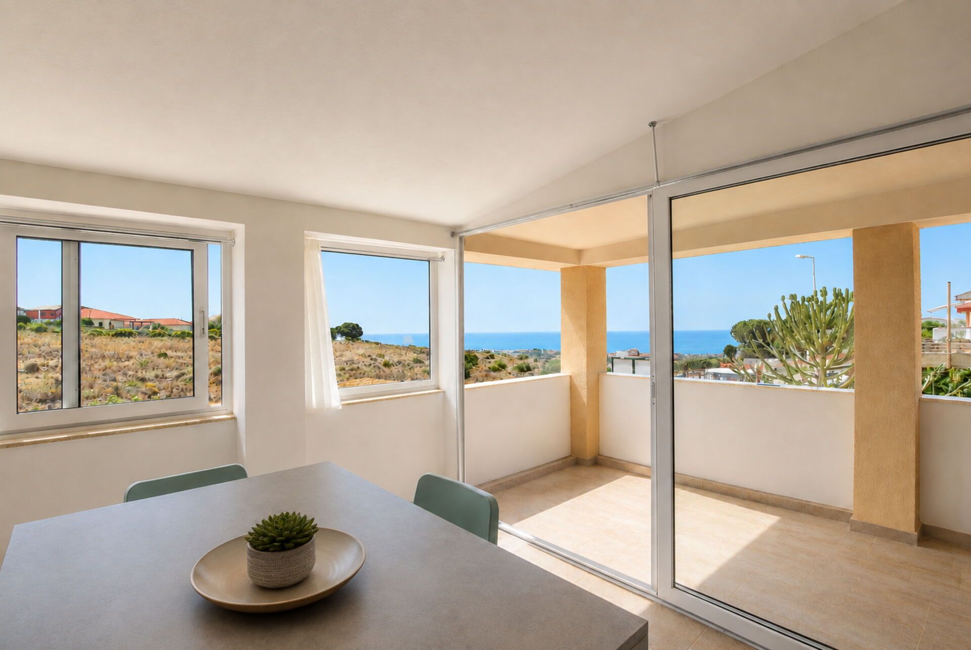 A modern interior with a dining area, large windows, and a view of the sea.