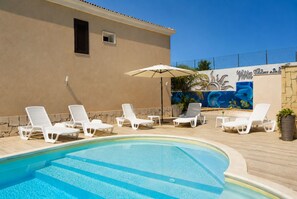 A swimming pool with lounge chairs and a mural on the wall. - Villa in Marina Di Ragusa with 1 bedrooms sleeps 4 (Marina Di Ragusa)