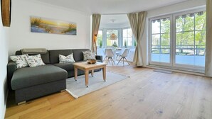 A living room with a sofa, coffee table, and a painting on the wall. - Seesternresidenz Apartment 19 - Seesternresidenz (Scharbeutz)