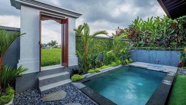 A modern outdoor pool area with a small covered seating area, surrounded by lush greenery and a clear sky. - Serene Villa With Private Pool and Rice Field Views (Tegallalang)