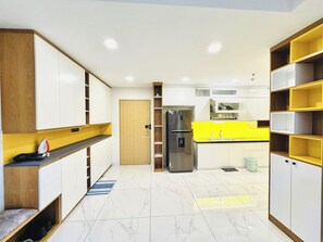 Eine moderne Küche mit weißen Schränken, einem Edelstahlkühlschrank, einer gelben Arbeitsplatte und einer Holztür.