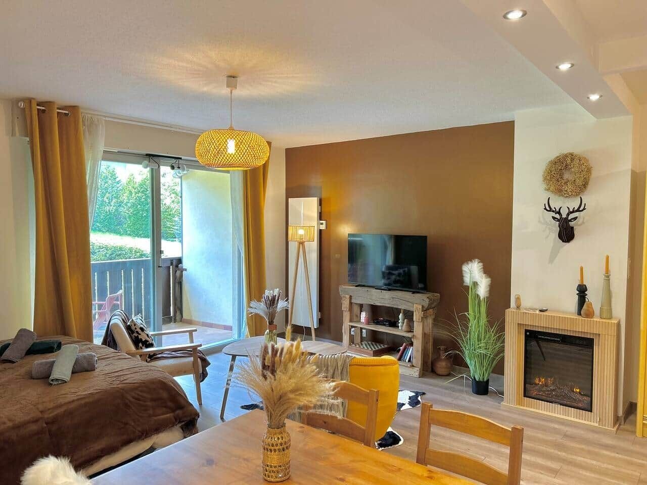 A modern living room with a sofa, a dining table, a fireplace, and a television.