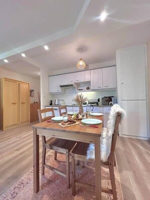 Un espace repas comprenant une table en bois, des chaises et un luminaire suspendu.