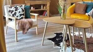 Una sala de estar con televisor, muebles de madera, alfombra de cuero de vaca y un adorno en la pared.
