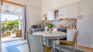 Una cocina moderna con armarios blancos, una mesa de comedor con sillas y vistas al exterior.
