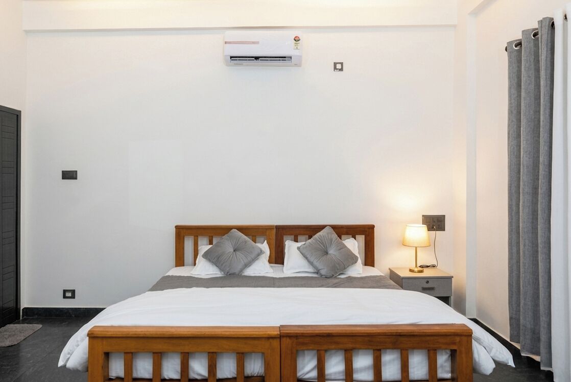 Un dormitorio con cama doble, una mesita de noche con lámpara, un equipo de aire acondicionado y un radiador.