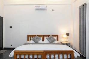 Un dormitorio con cama doble, una mesita de noche con lámpara, un equipo de aire acondicionado y un radiador.