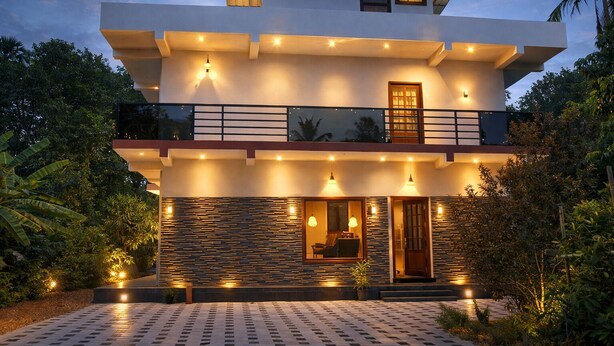 Uma casa moderna de dois andares com varanda, janelas amplas e iluminação externa.