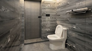 Une salle de bain équipée de toilettes, d’une douche et d’un porte-serviettes.