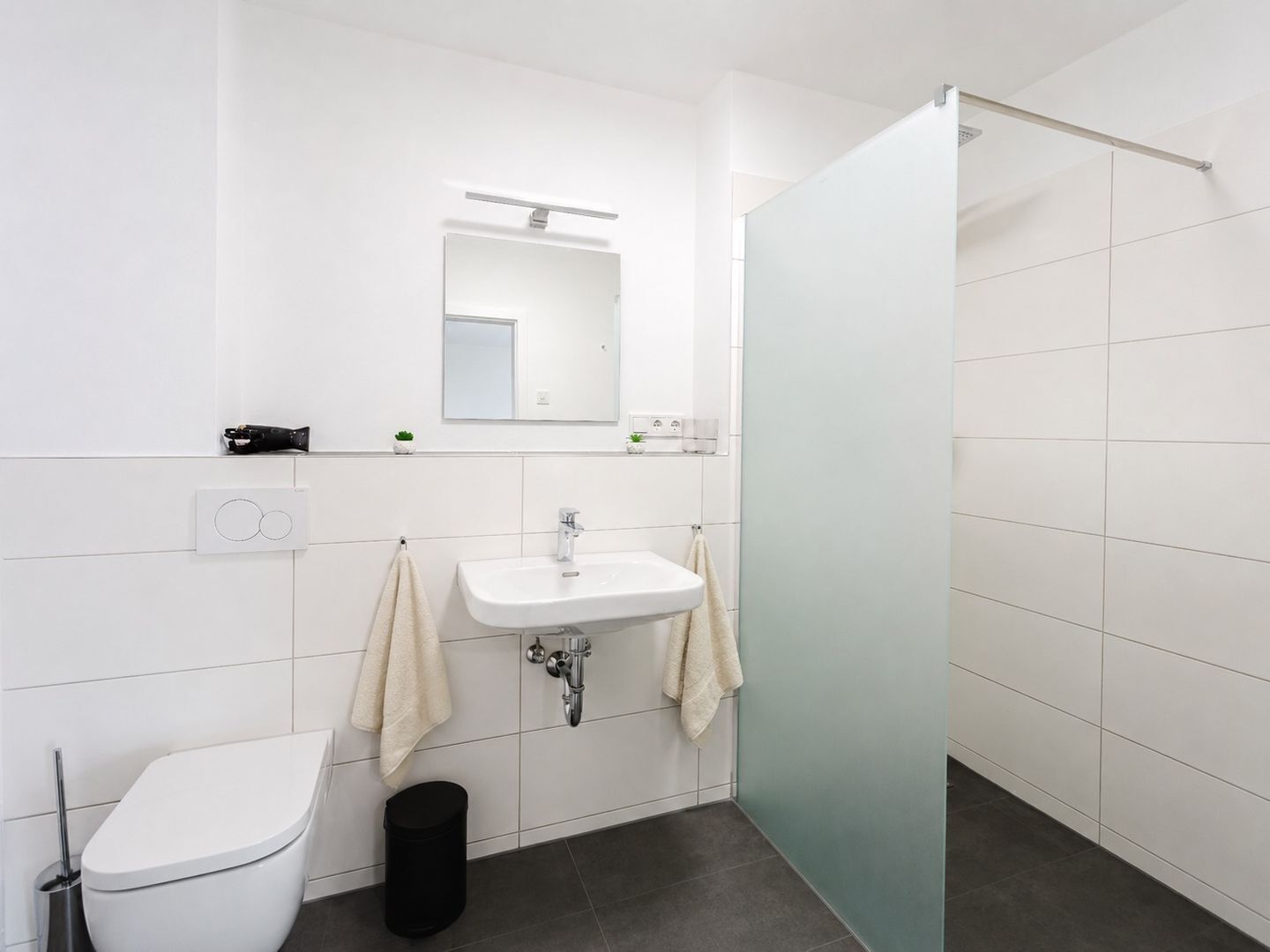 Ein modernes Badezimmer mit Toilette, Waschbecken und Dusche.