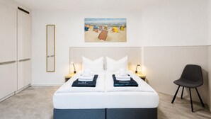 A hotel room with a bed, bedside lamps, a chair, a painting, and a wardrobe. - MEERholung House, Vacation Rental 2.5 - About 400 m from the beach, for up to 4 guests - House (Cuxhaven)