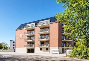 Ein mehrstöckiges Gebäude mit Ziegelverkleidung, Balkonen und blauem Himmel.