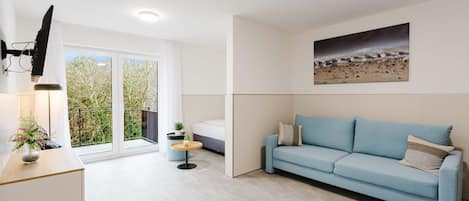A modern living room with a light blue sofa, a small round table, and a TV mounted on the wall.