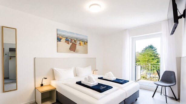 A hotel room with a bed, a bedside table, a chair, a painting, and a balcony with a view. - MEERholung Vacation Rental 2.3: Close to the Beach with a Balcony for Up to 4 Guests - MEERholung House (Cuxhaven)