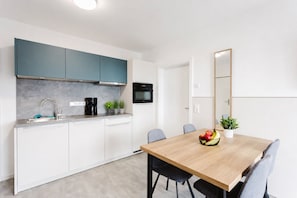A modern kitchen with white cabinets, a coffee maker, and a microwave. - MEERholung Apartment 2.3 near the beach with balcony for up to 4 guests - MEERholung (Cuxhaven)