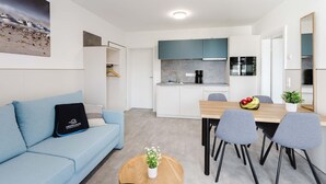 A modern apartment with a living area, kitchenette, and dining space. - MEERholung Vacation Rental 2.3: Close to the Beach with a Balcony for Up to 4 Guests - MEERholung House (Cuxhaven)
