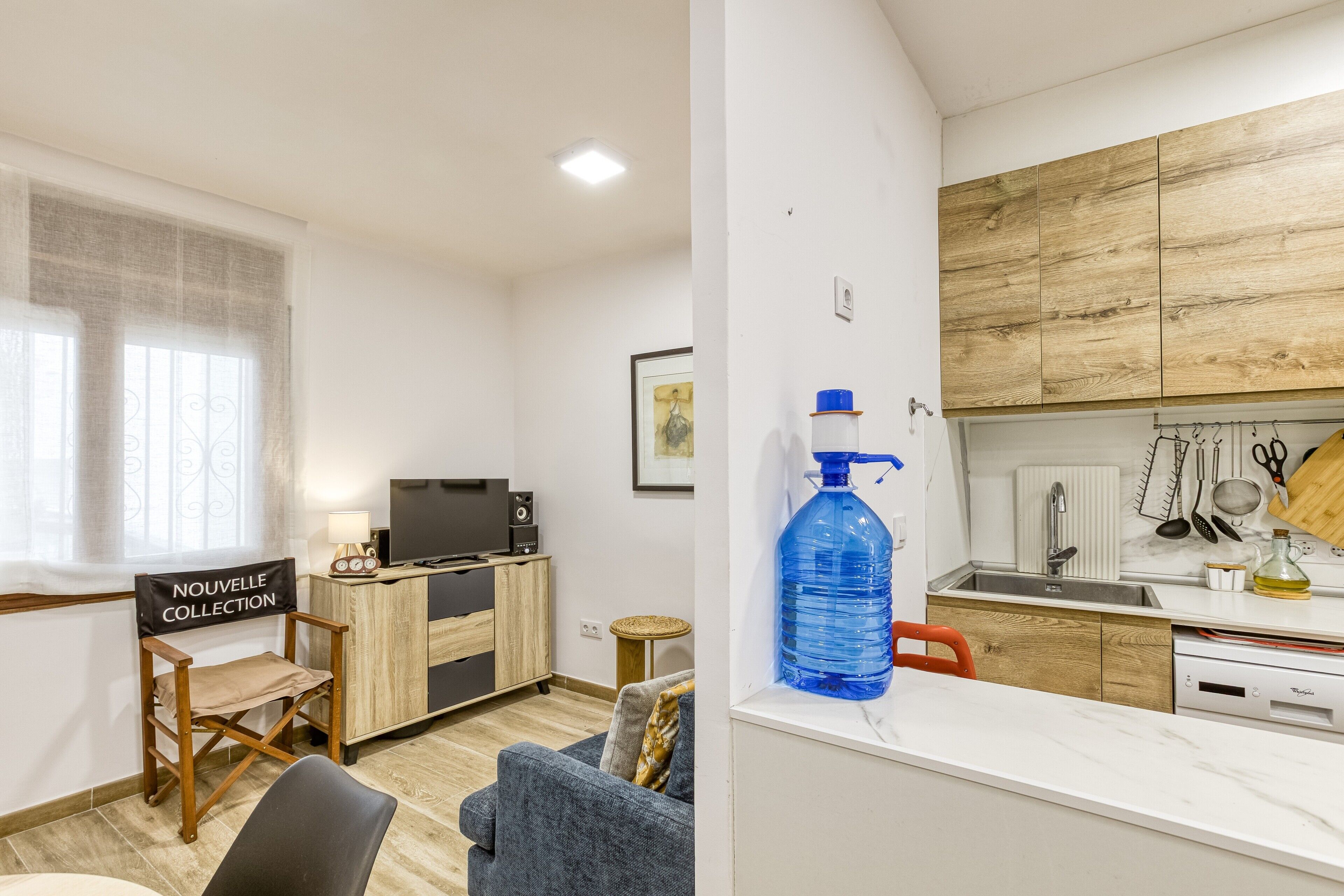Ett modernt vardagsrum med en soffa, en fåtölj, en tv och ett litet bord med en lampa.