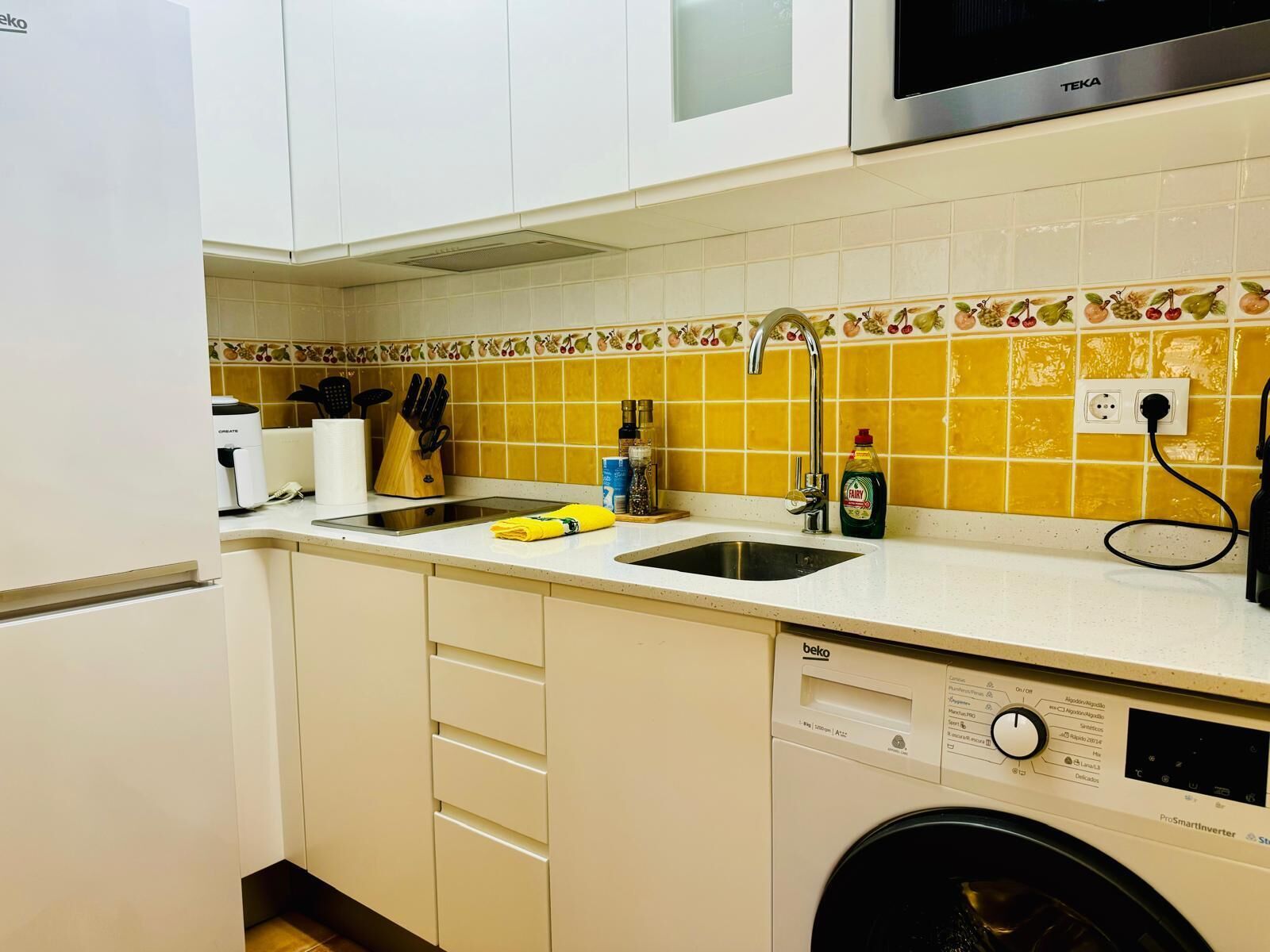Una cocina compacta equipada con lavavajillas, microondas y pileta.