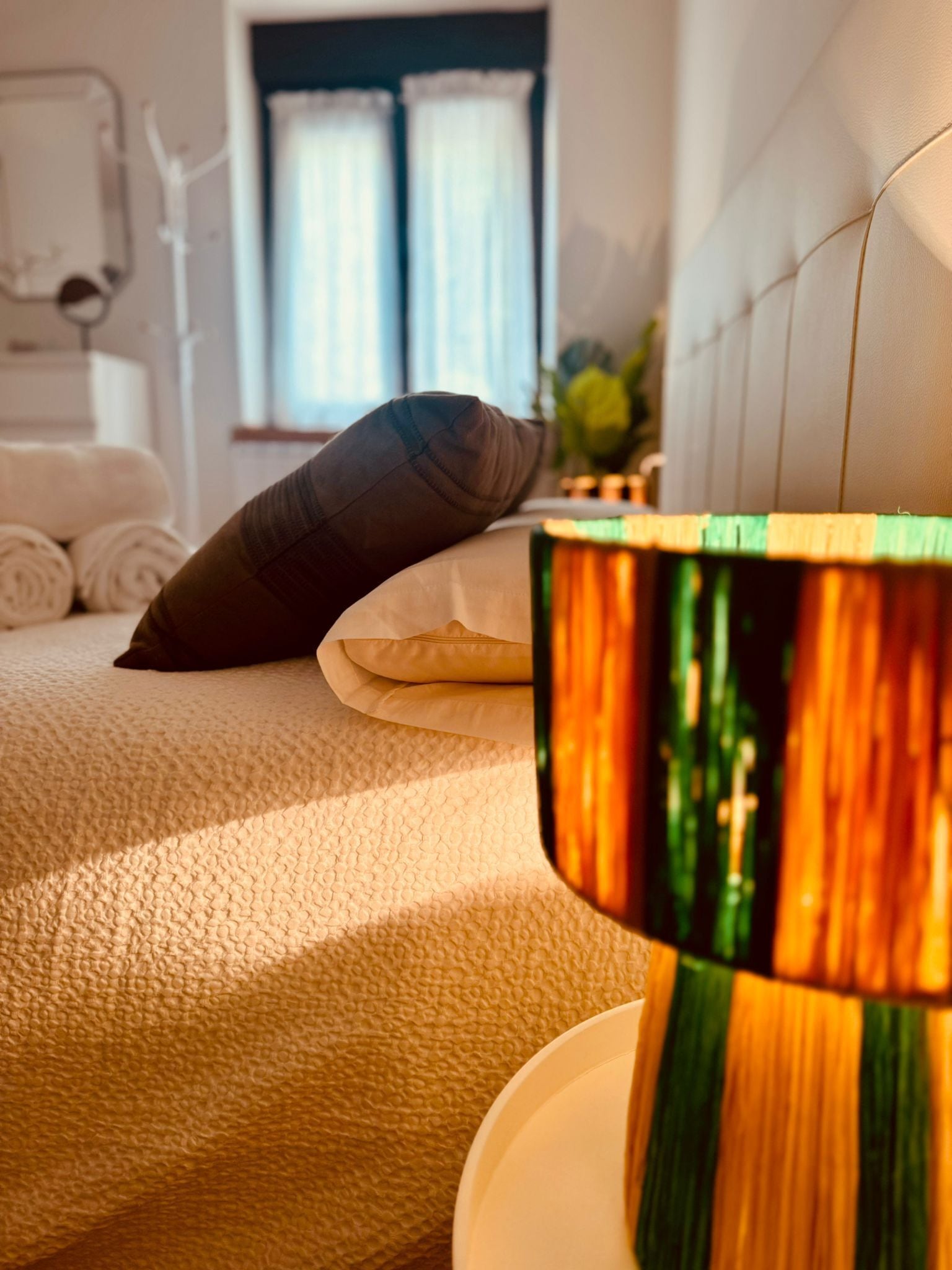 A bed with a pillow, a lamp, and a window with curtains.