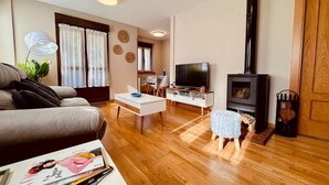 Una sala de estar con sofá, mesa de centro, televisión, chimenea y piso de madera.