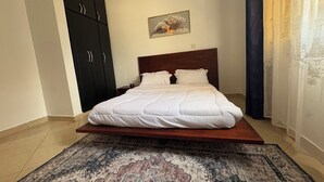Ein Schlafzimmer mit einem Bett, einem dunklen Wandschrank, einem gemusterten Teppich und einem Bild an der Wand.