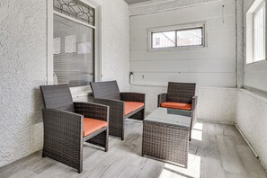 Een hoekzaal met rieten meubels, een glazen tafel en uitzicht door een raam.