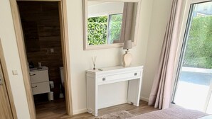 A bedroom with a bed, a desk, a mirror, and a view of greenery outside. - Exceptional villa, infinity pool, view of the marina and cliffs, close to beaches. (Albufeira)