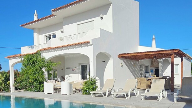 A modern white building with a swimming pool, outdoor seating, and a covered area. - Exceptional villa, infinity pool, view of the marina and cliffs, close to beaches. (Albufeira)
