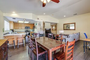 Eine geräumige Küche mit Holzausstattung, ein Essbereich mit großem Holztisch und ein Wohnzimmer mit Sofa und Fernseher.