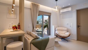 Ein modernes Wohnzimmer mit einer Couch, einem Sessel, einem Esstisch mit Obst und Blick durch eine Glastür.