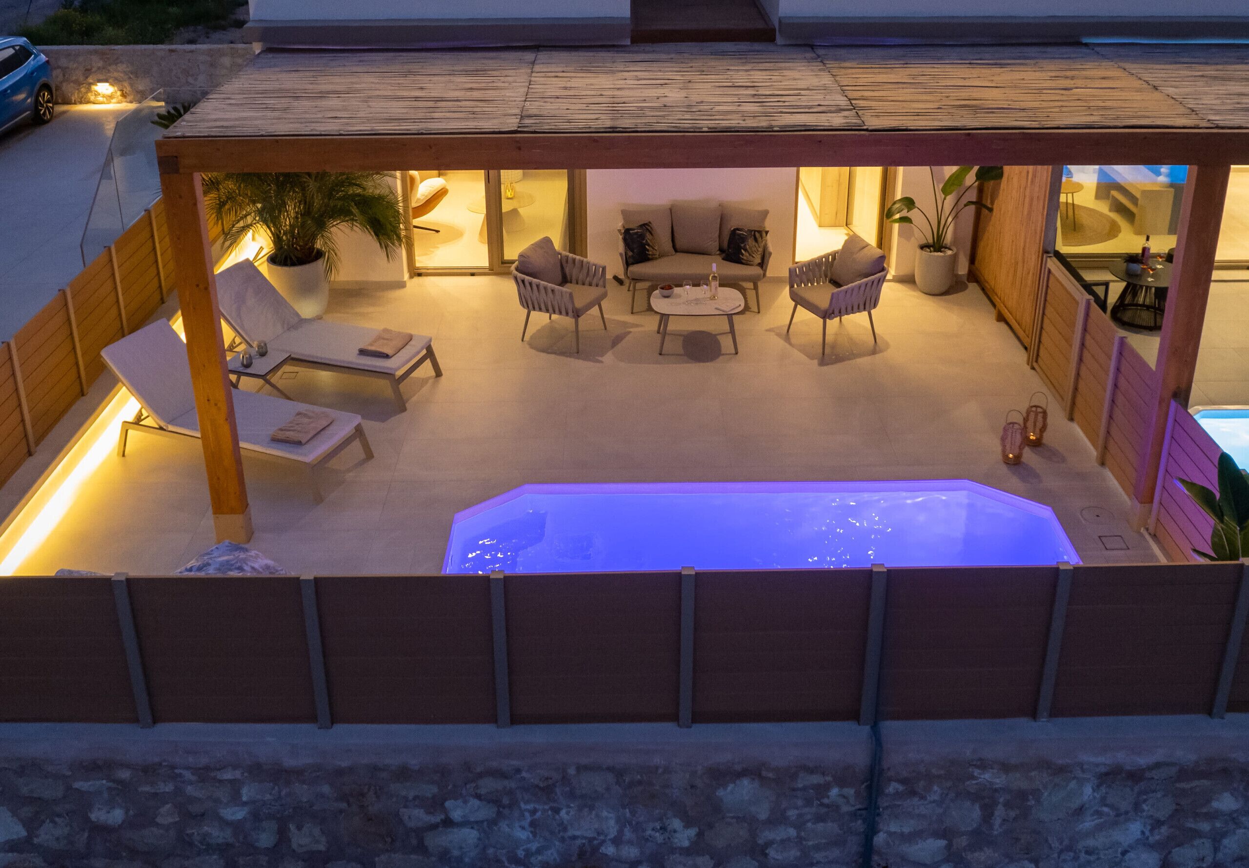 A rooftop patio with a hot tub, seating area, and potted plants.