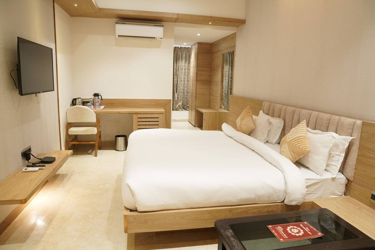 Ein Hotelzimmer mit Bett, Schreibtisch, Stuhl, Fernseher und einer Kaffeemaschine.