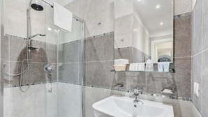 Un bagno moderno con doccia vetrata, lavandino bianco e pannello di piastrelle.