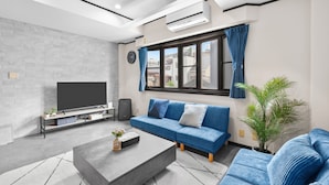 Een moderne woonkamer met een bank, een salontafel, een televisie en een potplant.