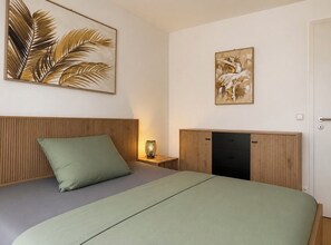 Une chambre à coucher avec un lit, une table de chevet avec une lampe et des œuvres d’art accrochées aux murs.