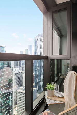 A balcony with a city view, a small table with a plant, a glass, and a towel. - Stylish Pet-friendly 2br, Walk to Southern Cross (Melbourne)