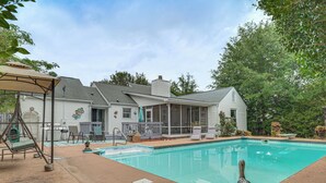 Un jardin avec une piscine, des meubles de patio et un espace salon abrité.