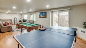 Una sala de estar con mesa de billar, sofá y mesa de futbolín.