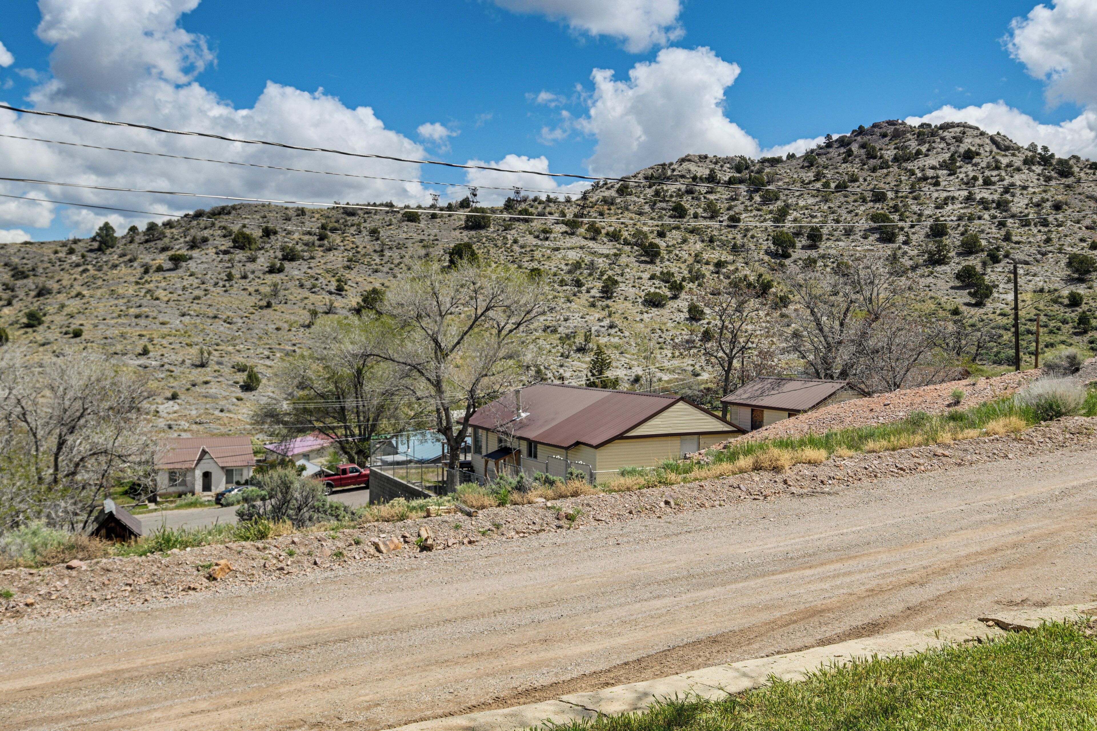 A rural road with houses on a hillside, power lines overhead, and a clear sky.