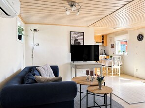 A modern living room with a sofa, a TV, a small table with candles, and a kitchen in the background. - Skeaberg by Interhome (Halmstad)