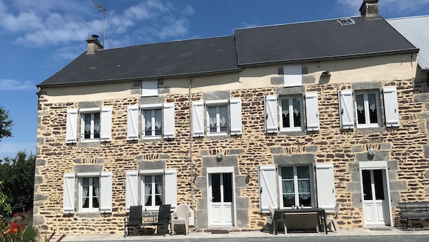 Un bâtiment en pierre de deux étages, doté de nombreuses fenêtres et d’un toit plat.