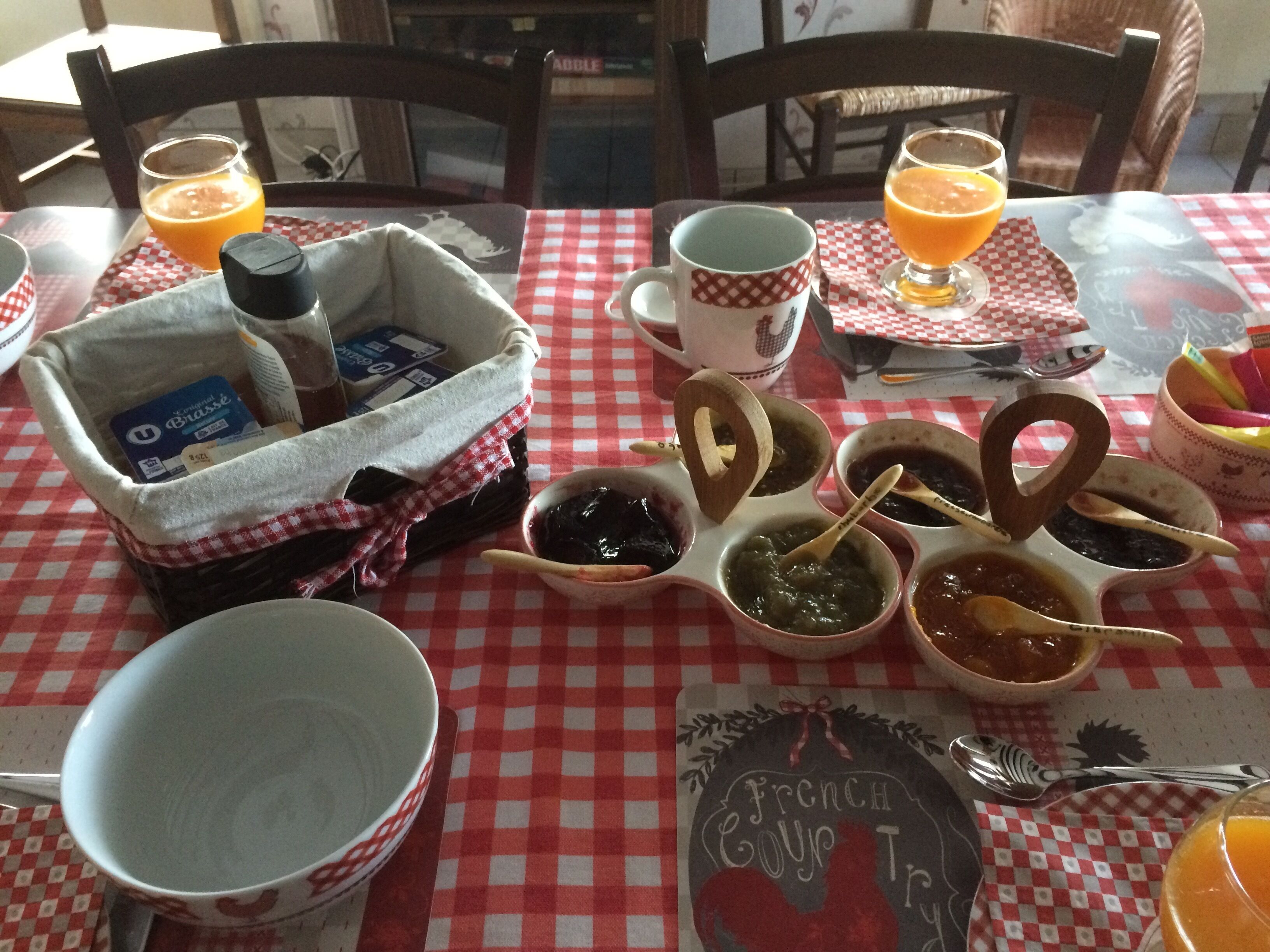 A table set with condiments, a coffee mug, and glasses of orange juice.