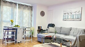 Una sala de estar con sofá, mesa de centro y comedor con sillas.