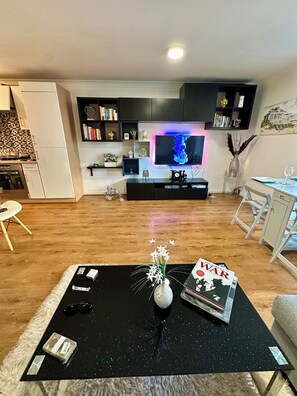A modern living room with a black coffee table, a vase with flowers, a magazine, and a television. - Bright & Cosy Home in Thornaby near Tees River (Thornaby)