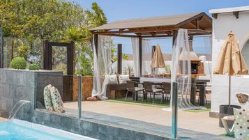 Una piscina con pérgola y zona de estar al aire libre.