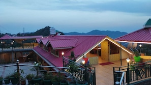 Um hotel com vários edifícios de telhado vermelho, áreas de estar ao ar livre e vista para montanhas ao fundo.