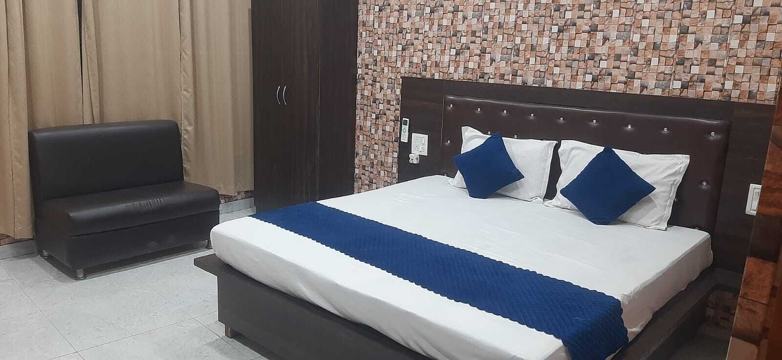 A bedroom with a bed, a nightstand, a wardrobe, and a sofa.