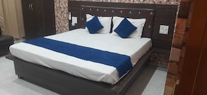 Una cama con una colcha blanca y azul, dos almohadas azules y un cabecero oscuro.